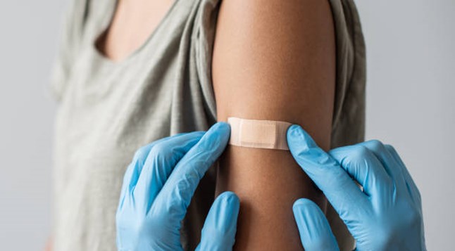 Woman with a bandage on her arm following a vaccination.
