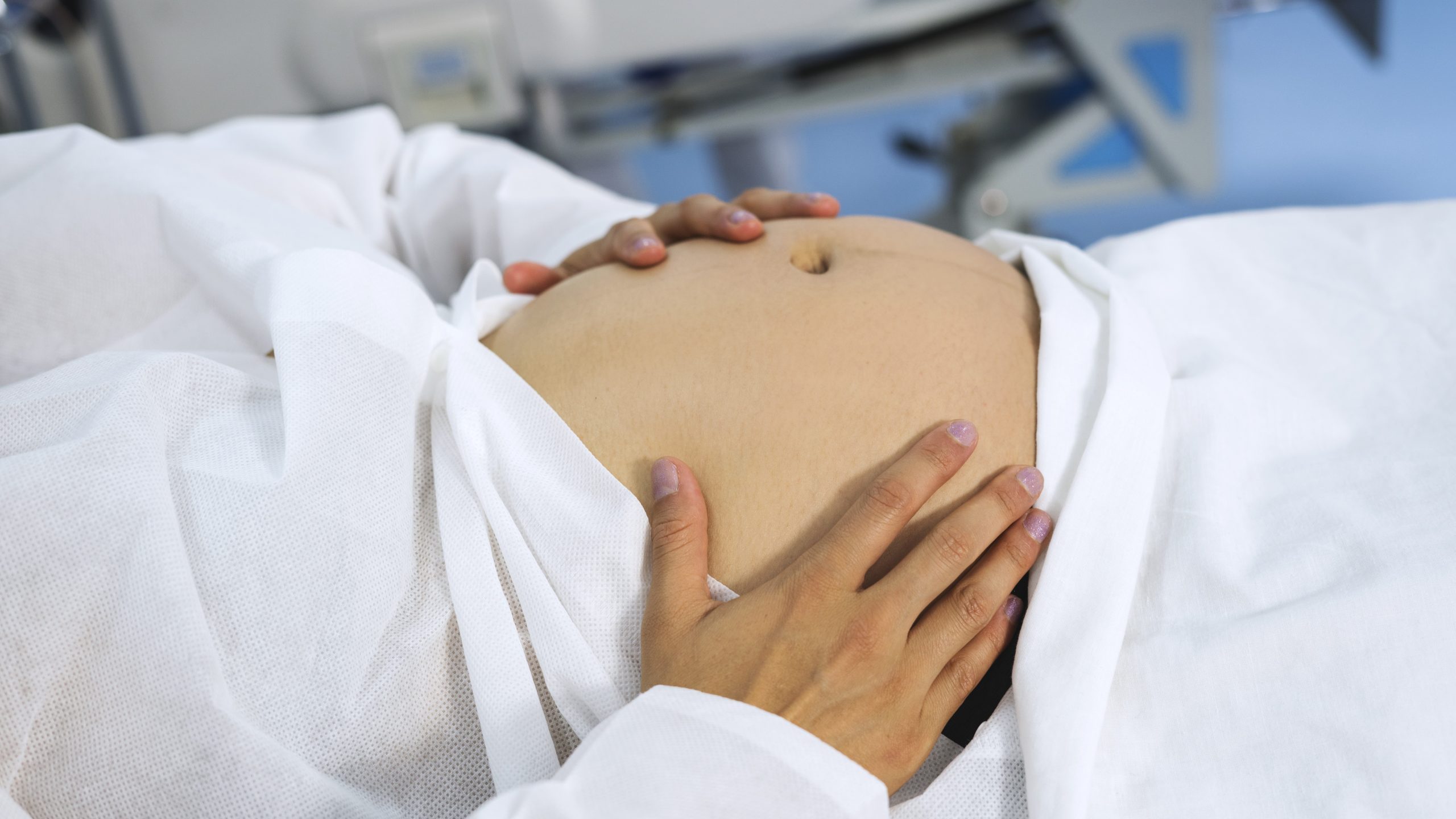 Pregnant woman holds her belly in a clinic.