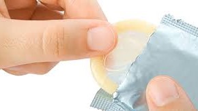 A person removes a male condom from its packaging.
