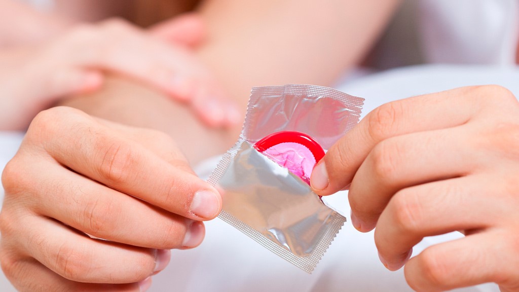 A person opens a male condom package.
